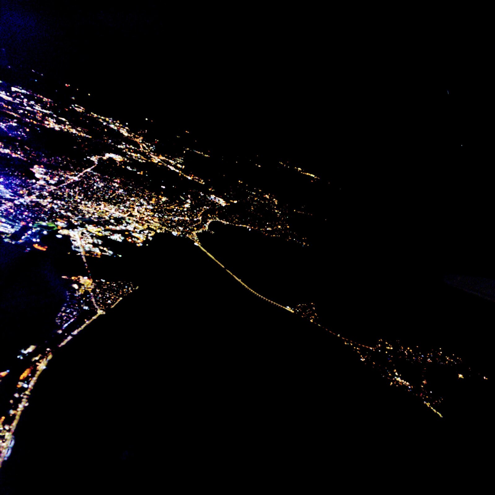 Where the city meets the water at night, bridges and roads form webs and strings of beads of light